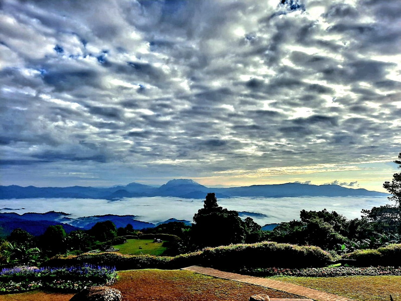 Mountain View with Cloudy Sky at Huai Nam Dang National Park Cloud-covered sky with distant mountains and a garden with a pathway and bushes at Huai Nam Dang National Park.
