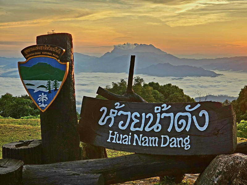 Huai Nam Dang Viewpoint at Huai Nam Dang National Park Wooden signboard with park emblem overlooking a cloud-filled valley at sunset at Huai Nam Dang National Park.