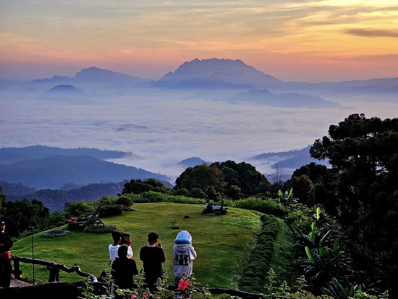 Visitors viewing mountains and fog from a scenic overlook at sunset at Huai Nam Dang National Park.