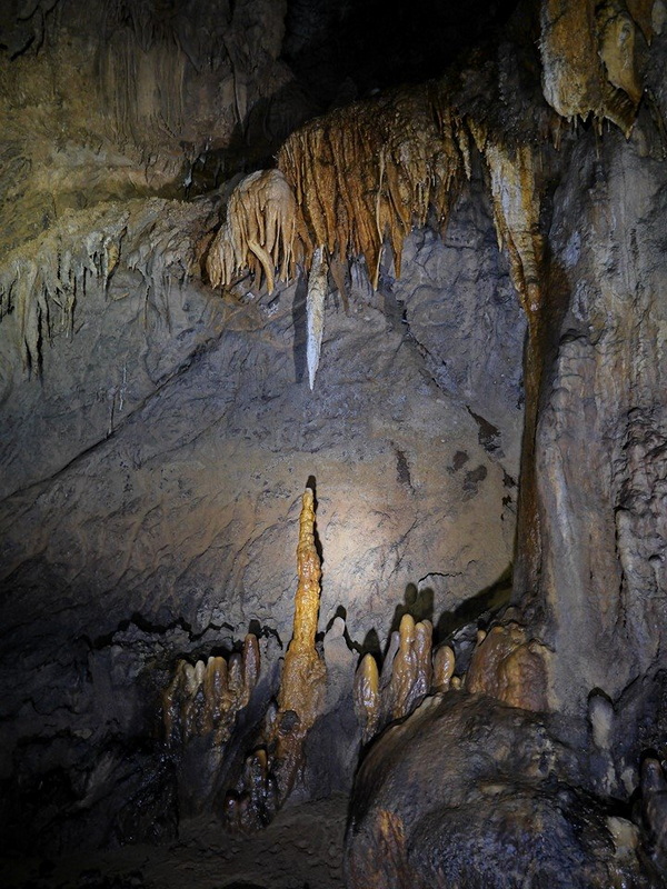 Inside a cave showing stalactites and stalagmites with focused lighting at Mae Lana Cave.