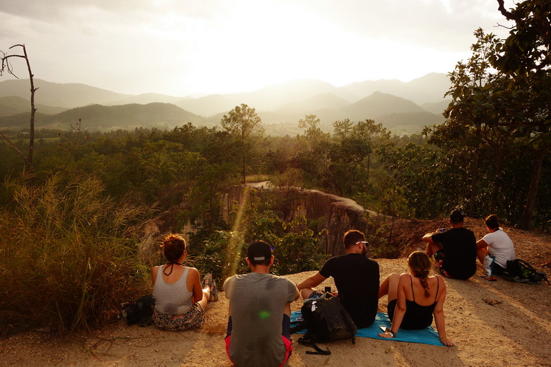 Group of five people watching sunset over mountains from a natural viewpoint at Pai Canyon.