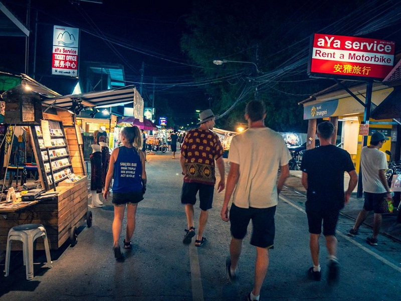Night Market Street Scene at Pai Walking Street Night scene of people walking past market stalls with signs on a bustling street at Pai Walking Street.
