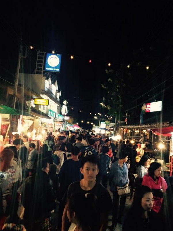 Night market filled with people, booths, and colorful lights at night at Pai Walking Street.