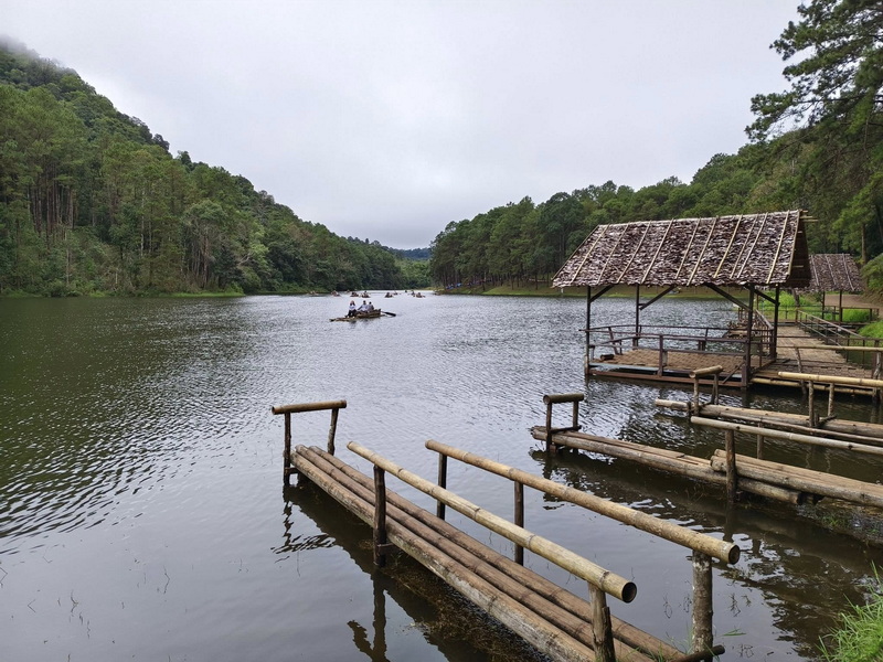 Bamboo docks and pavilions beside a peaceful lake surrounded by green trees at Pang Ung.