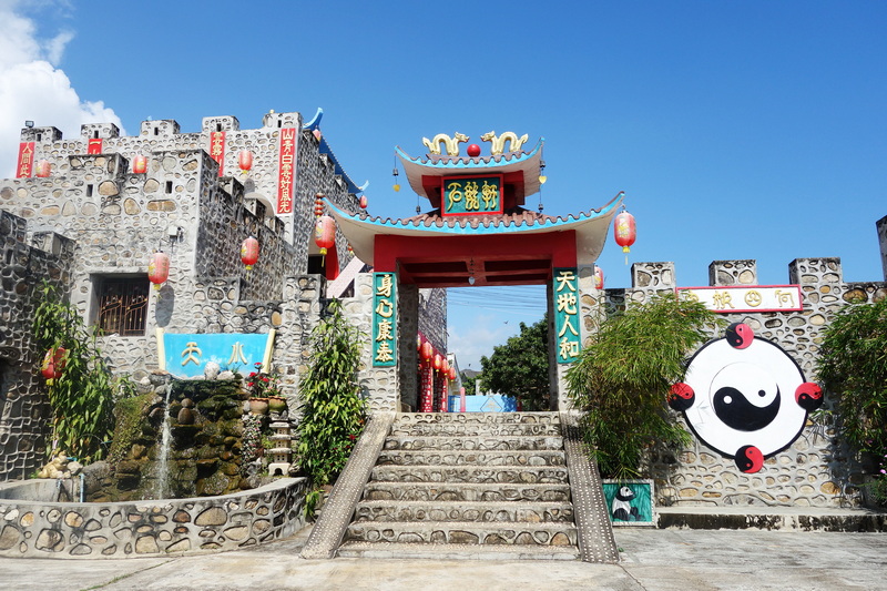 Stone steps and traditional Chinese entrance with lanterns and greenery at Santichon Village.