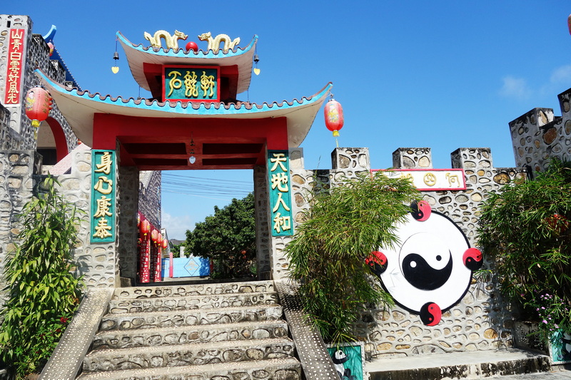 Traditional Chinese-style entrance gate with lanterns and greenery at Santichon Village.
