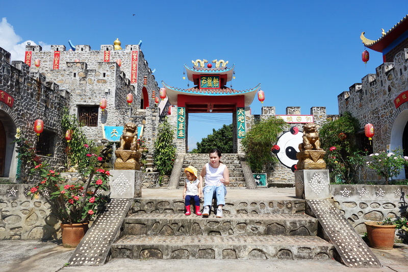Two children sitting on stone steps with lion statues and Chinese-style gate in the background at Mae Hong Son.