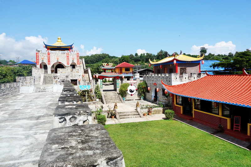Temple complex with colorful roofs, stone steps, and decorative elements under a bright sky at Mae Hong Son.