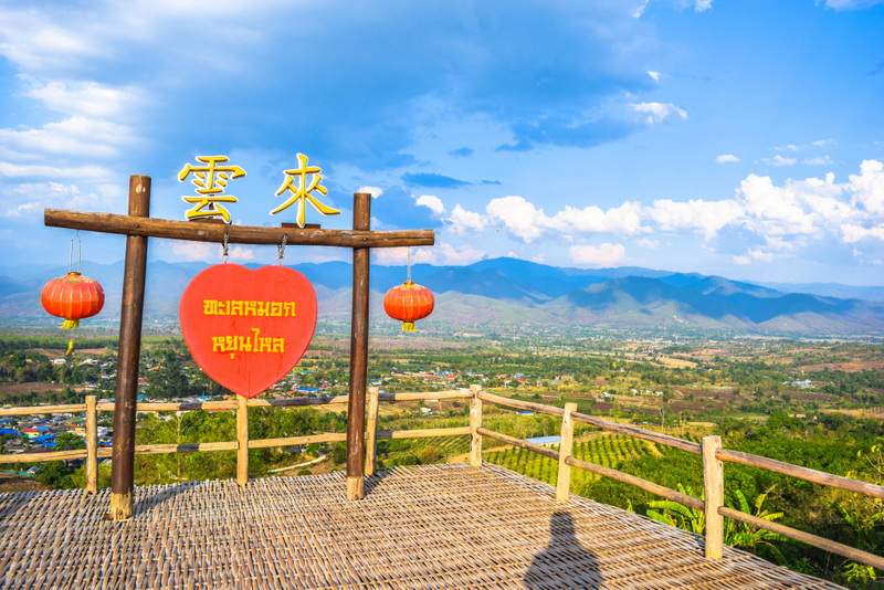 Scenic Viewpoint Overlooking Valley at Santichon Village Wooden viewpoint with lanterns overlooking valley and mountains under blue sky at Santichon Village.