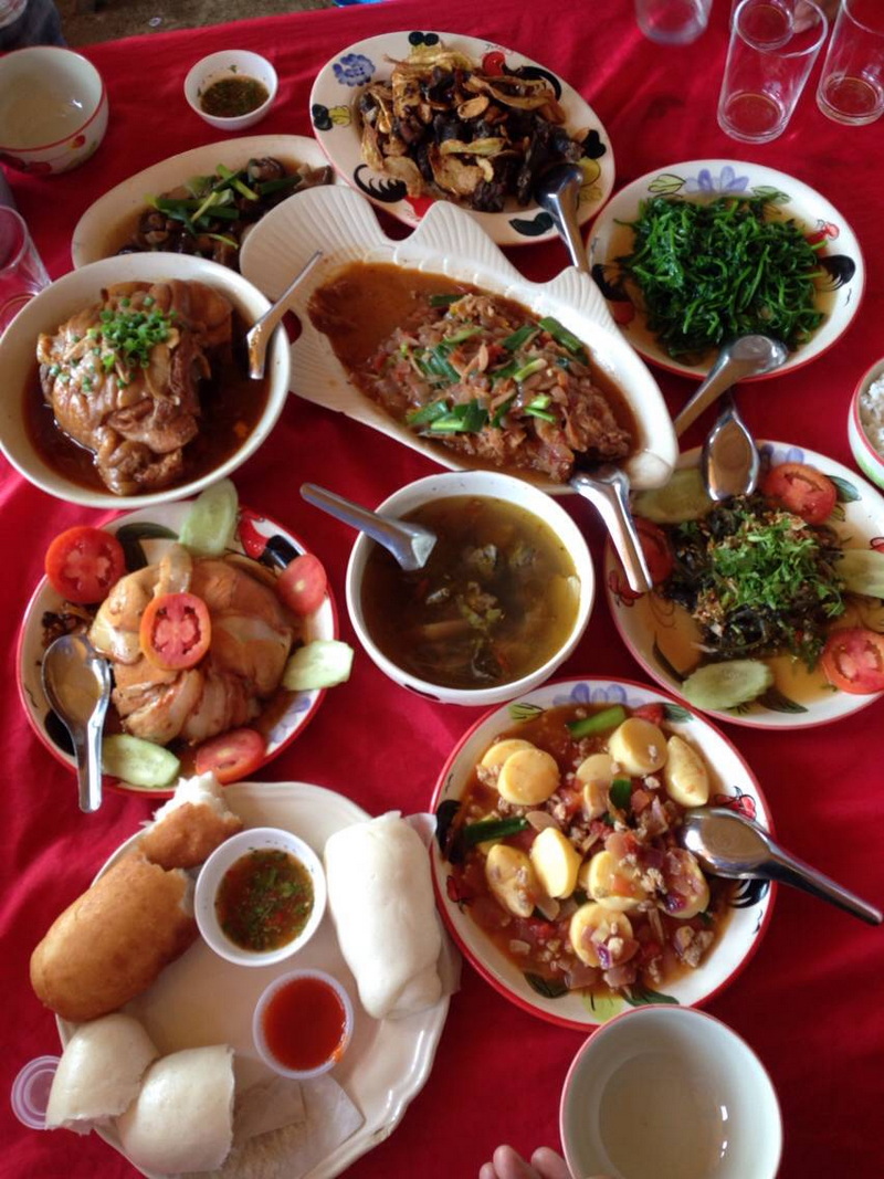 Assorted bowls of Asian dishes with vegetables, meats, and soups on a red tablecloth at Santichon Village.