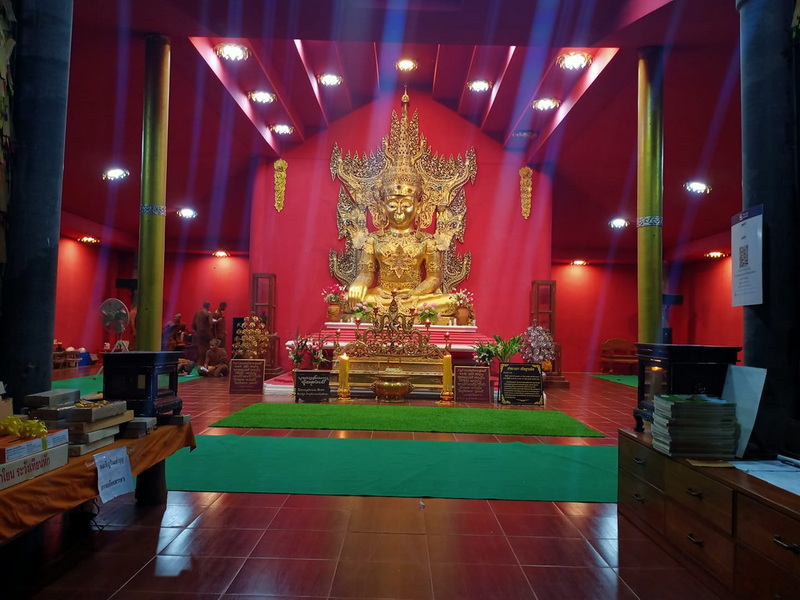 Golden Buddha statue with intricate details inside a red-walled temple at Su Tong Pae Bridge.