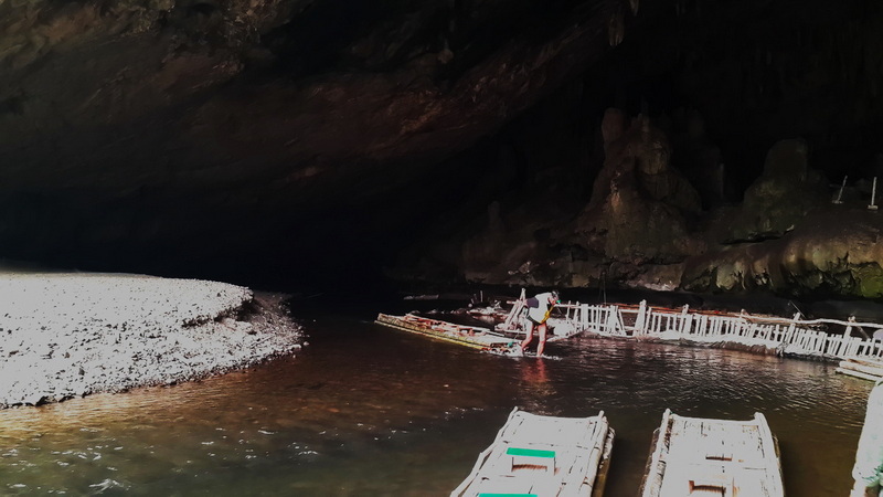 People on boats inside a dark cave with rocky walls and water at Mae Hong Son.