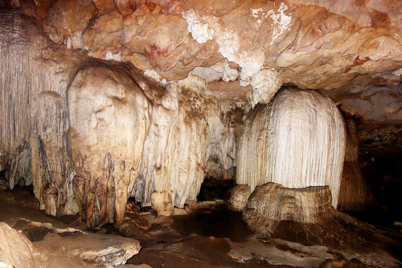 Limestone cave interior with stalagmites and stalactites and a water pool at Tham Lod Cave.