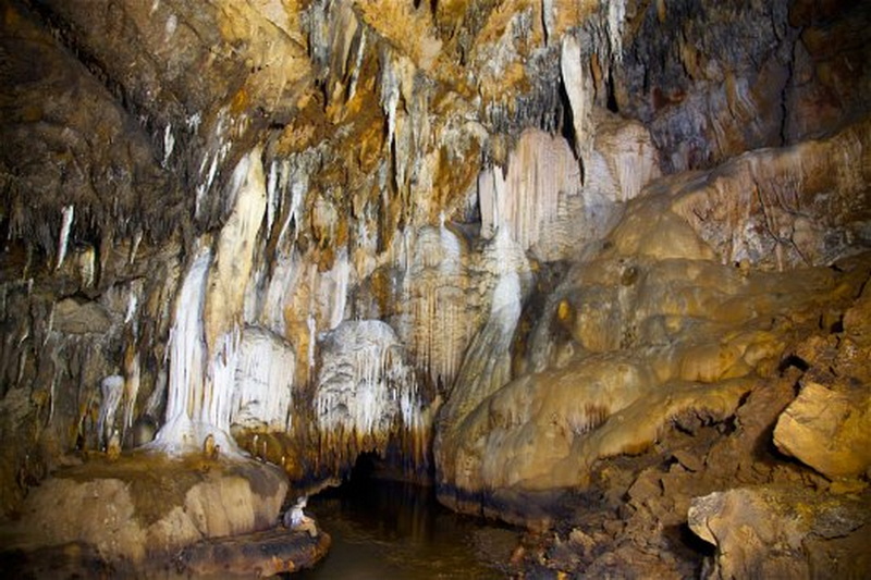 Cave Interior with Mineral Formations at Tham Lod Interior of a limestone cave with stalactites and mineral stalagmites over a small water pool at Tham Lod.