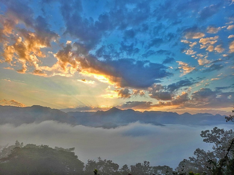 Sunset Over Mountain Range at Wat Phra That Doi Kong Mu Mountains visible through fog with a vibrant sunset sky and scattered clouds at Wat Phra That Doi Kong Mu.