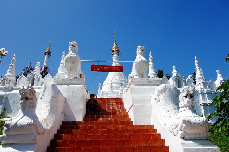 White staircase with lion statues leading to a stupa under clear blue sky at Wat Phra That Doi Kong Mu.