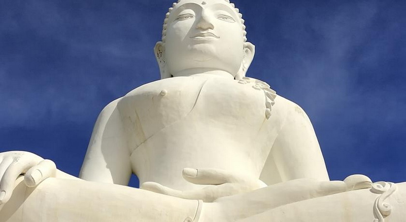 Close-up view of a white Buddha statue with a peaceful expression under a clear sky at Wat Phra That Mae Yen.