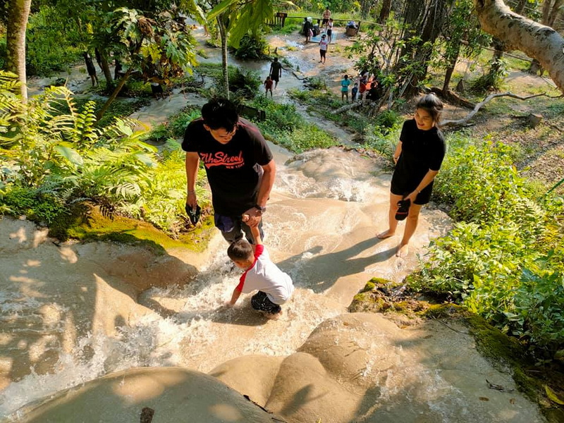 Child Playing in Water Stream at Bua Tong Sticky Waterfall Child and adult standing in a shallow water stream with lush plants around at Bua Tong Sticky Waterfall.