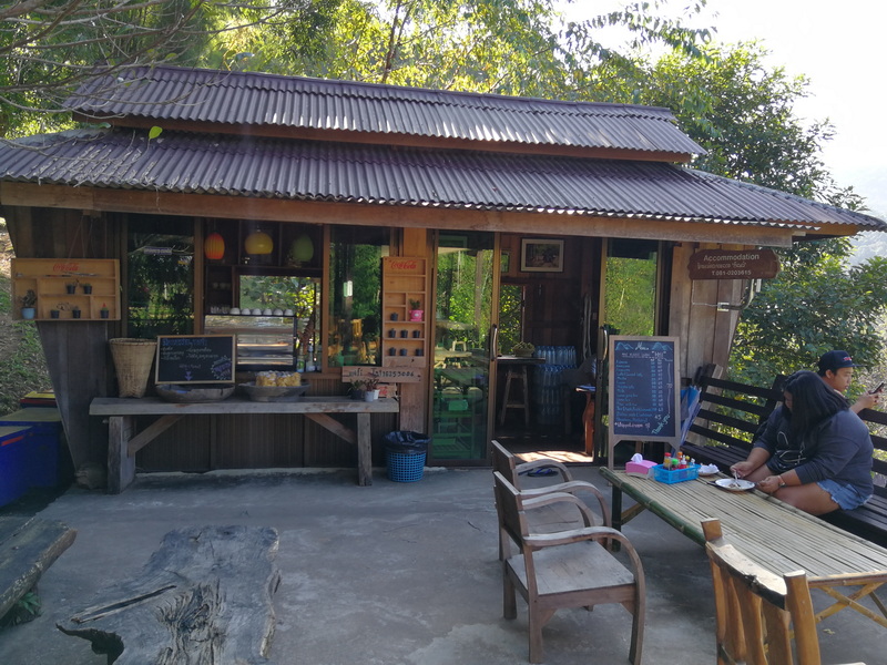 Small wooden café with greenery and outdoor seating, serving visitors at Mae Klang Luang Village.