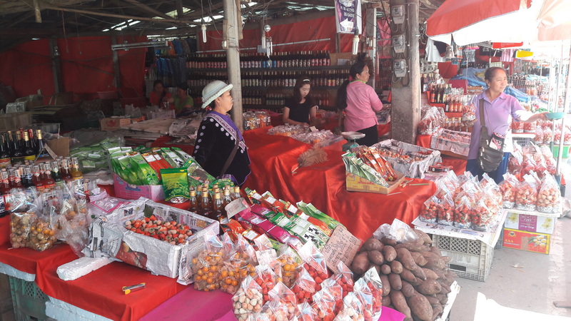 Outdoor Market with Snacks at Doi Inthanon Hmong Market Market stall with various packaged snacks and vendors under red parasols at Doi Inthanon Hmong Market.