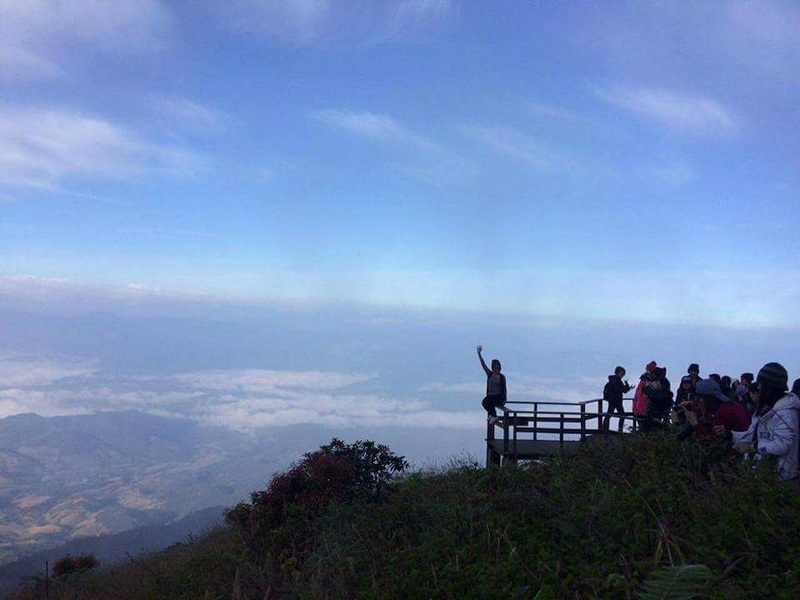 Mountain Viewpoint Over Clouds at Kew Mae Pan Nature Trail People standing and waving on a mountain viewpoint overlooking clouds and sky at Kew Mae Pan Nature Trail.