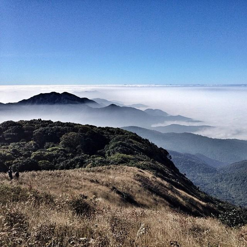 Scenic view of mountains with grassy hills and mist in the valleys under a clear sky at Kew Mae Pan.