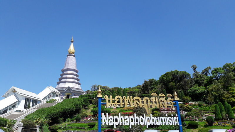 A pagoda with a tall spire and surrounding greenery under a clear sky at King and Queen Pagodas.