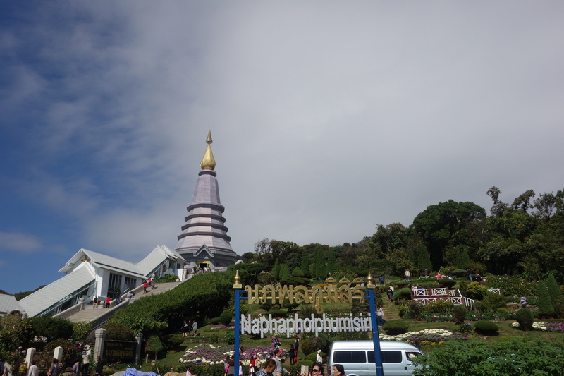 Tall white pagoda with golden spire surrounded by gardens and trees at King and Queen Pagodas Doi Inthanon.