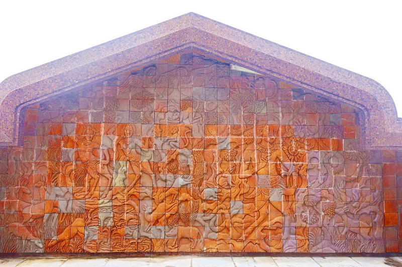 Large carved stone wall with detailed relief sculptures of human figures and patterns at King and Queen Pagodas.