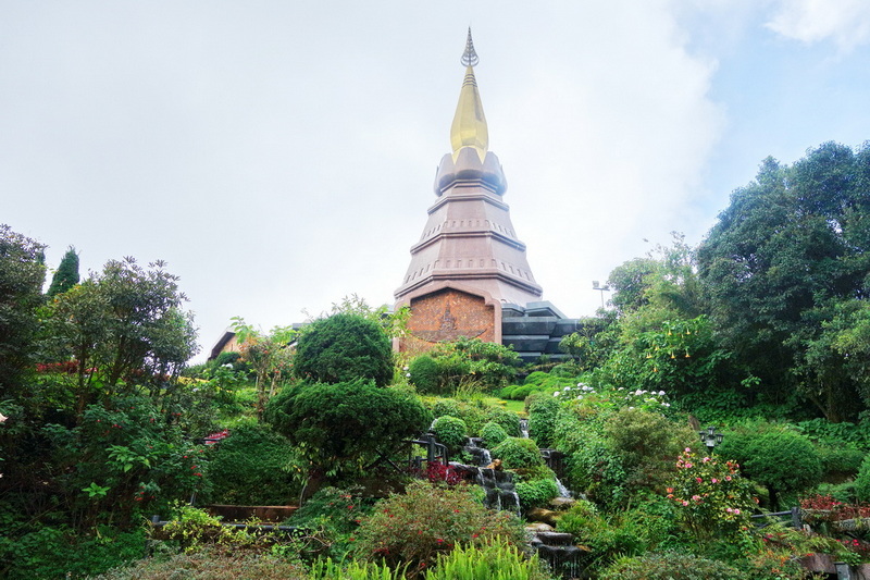 Stupa in Serene Garden Scene at King and Queen Pagodas Doi Inthanon Tall stupa with golden spire amidst lush garden and waterfall at King and Queen Pagodas Doi Inthanon.