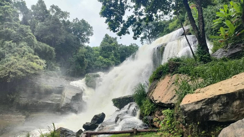 Waterfall cascading over rocks amidst dense green forest at Mae Klang Waterfall.