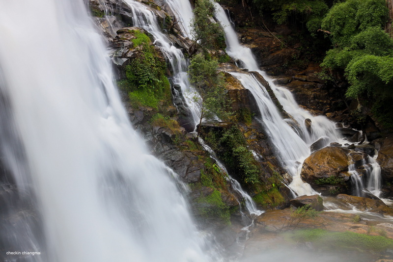 Waterfall flowing over rocks with lush green plants nearby at Wachirathan Waterfall.