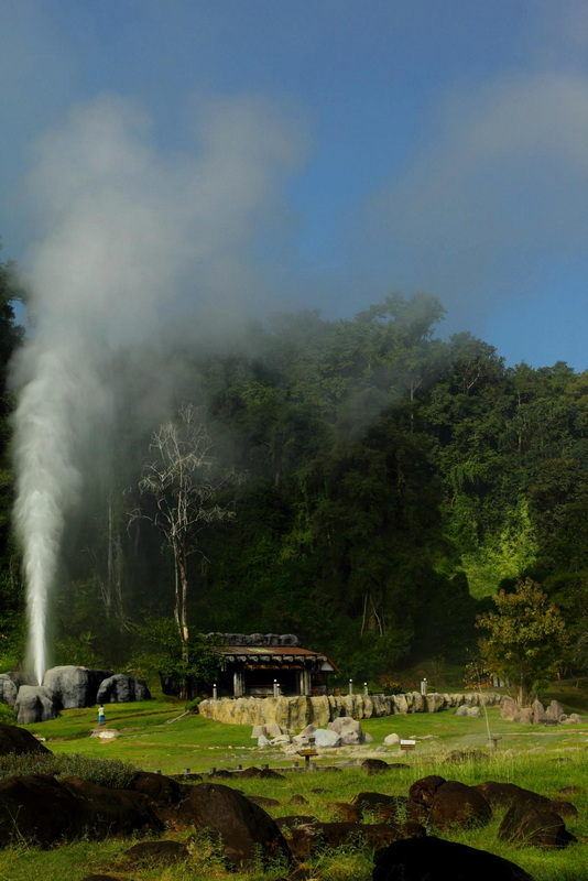 Steam rises from a geothermal hot spring surrounded by greenery and rocks at Doi Pha Hom Pok National Park.