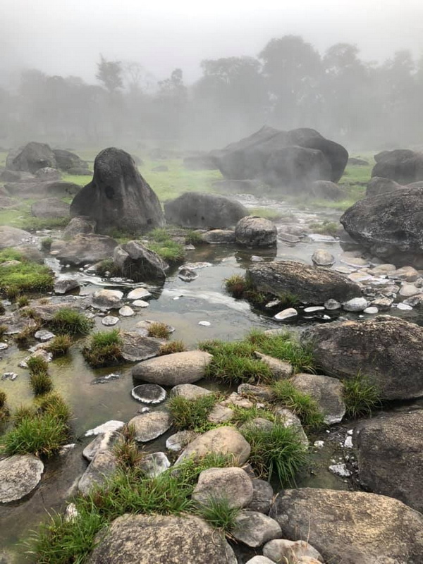 Misty Rocky Landscape at Fang Hot Spring Rocky landscape with pools of water, grass patches, and misty background at Fang Hot Spring.