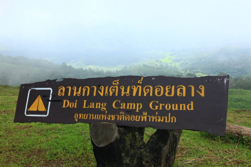 Doi Lang Campground Sign at Doi Pha Hom Pok National Park Wooden signboard with national park name, mountain fog in the background at Doi Pha Hom Pok National Park.