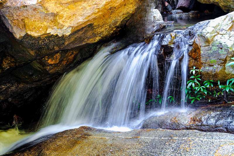 Small Waterfall in Nature at Huai Kaew Waterfall Stream flowing over rocks with green plants nearby in a natural setting at Huai Kaew Waterfall.
