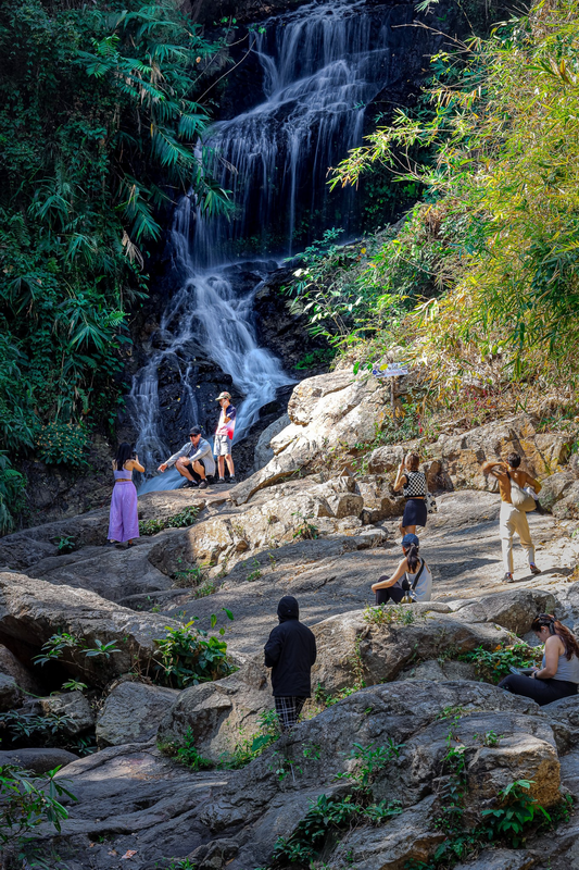 Visitors at a Waterfall at Huai Kaew Waterfall People enjoying the waterfall and rocky area in lush jungle surroundings at Huai Kaew Waterfall.