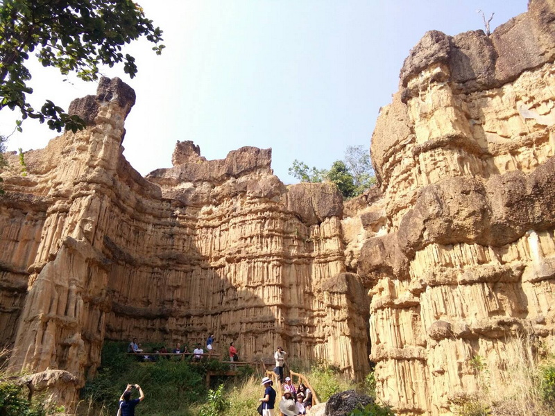 Striking Rock Formations at Pha Chor Striated rock cliffs with visitors exploring the base outdoors at Pha Chor.