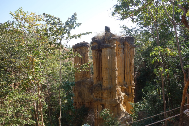 Tall rock formation surrounded by trees and lush greenery at Phar Choi.