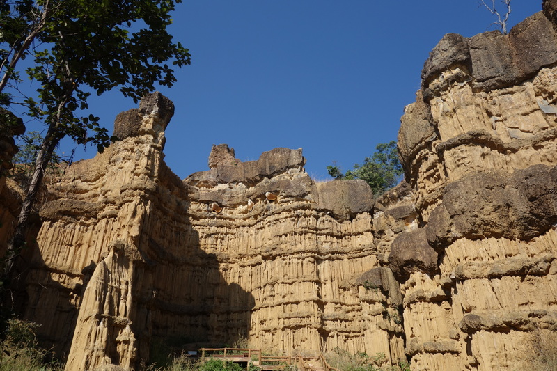 Tall layered rock formations with trees and a clear sky at Mae Wang National Park.