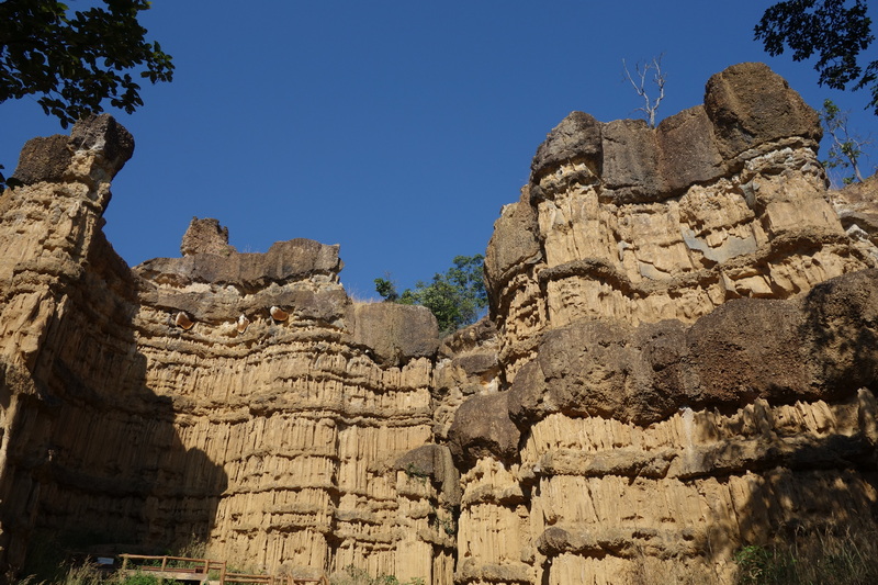 Cliff faces with layered textures and a clear blue sky above at Phar Choi.
