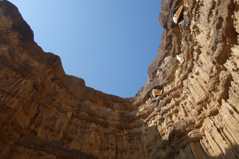 View of blue sky through a rocky cave opening with rugged walls inside at Pha Chor.