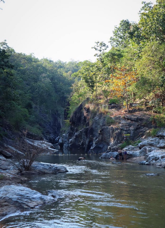 Rocky river with trees on both sides and people swimming in the water at Ob Khan National Park.