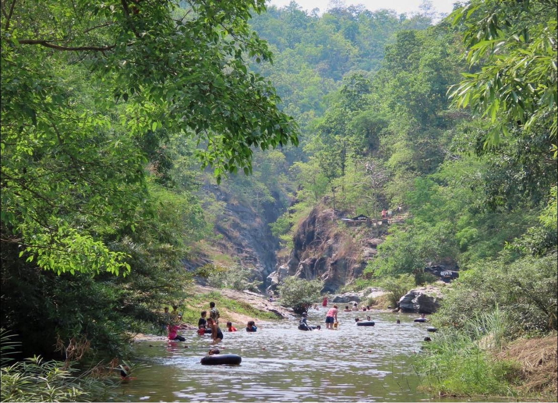 People enjoying swimming in a calm river with dense forest around at Ob Khan National Park.