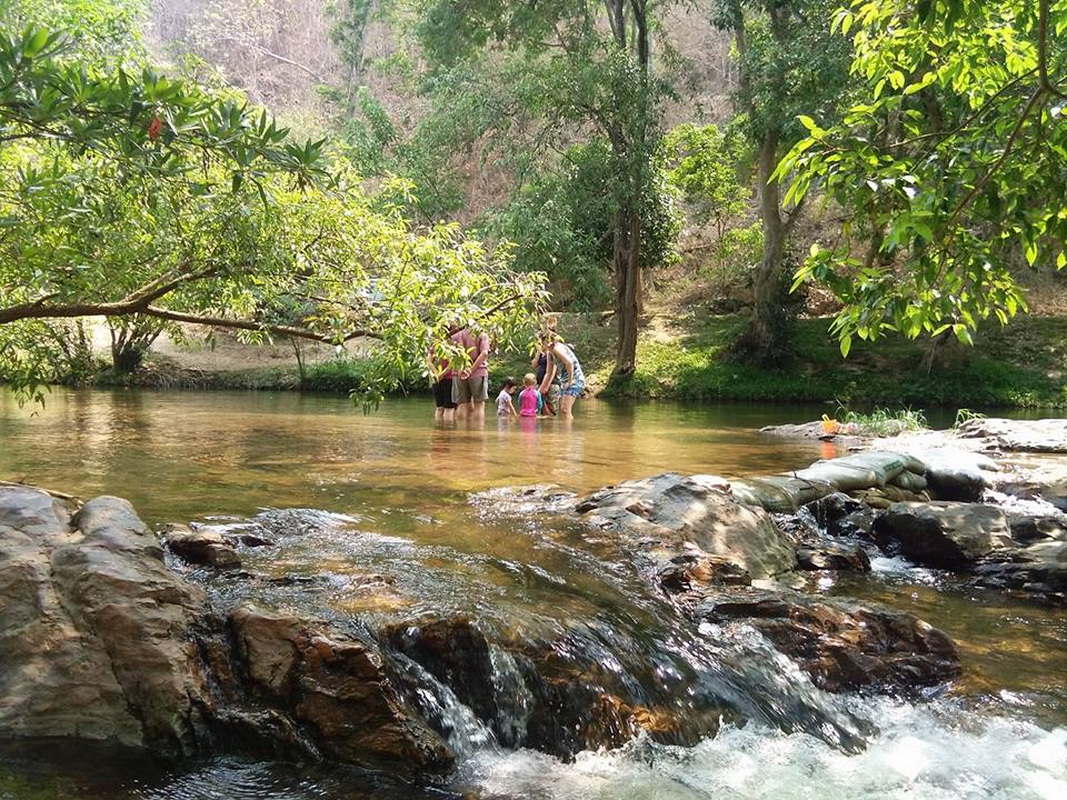 People standing in a shallow river with greenery and rocks around them at Ob Khan National Park.