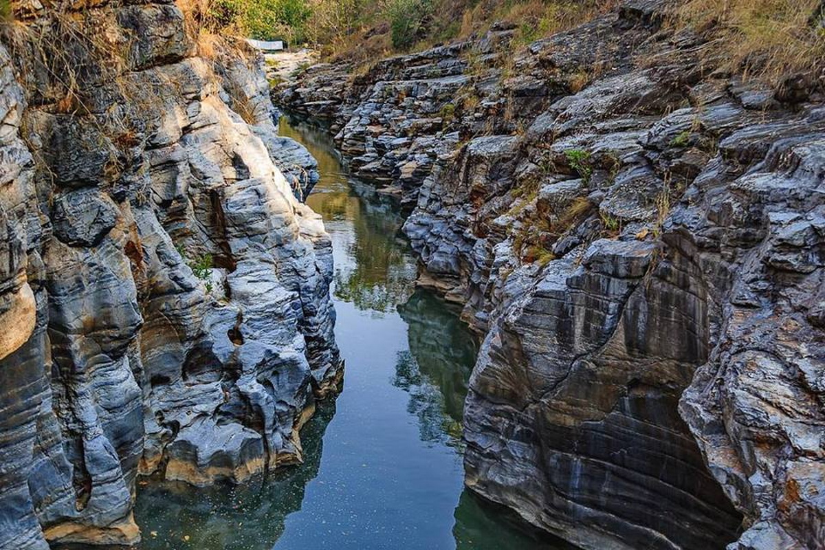 Narrow canyon with rocky walls and a small water stream flowing through at Ob Khan National Park.