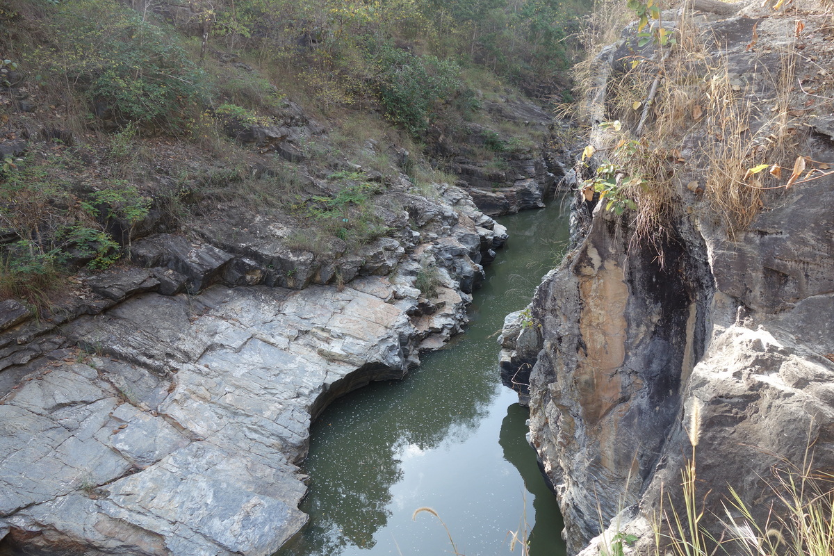 Narrow river running through a rocky canyon with cliffs and sparse plants at Ob Khan National Park.
