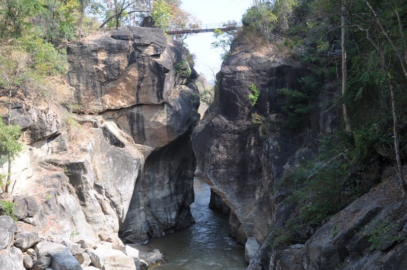 Scenic Canyon with River at Ob Luang National Park Narrow river flowing through a rocky canyon with bridge overhead and greenery at Ob Luang National Park.