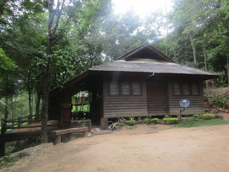 Wooden cabin with trees and sunlight in a forested area at Ob Luang National Park.