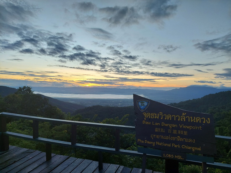 Scenic mountain view with clouds and sunrise from a viewpoint with a sign at Pha Daeng National Park.